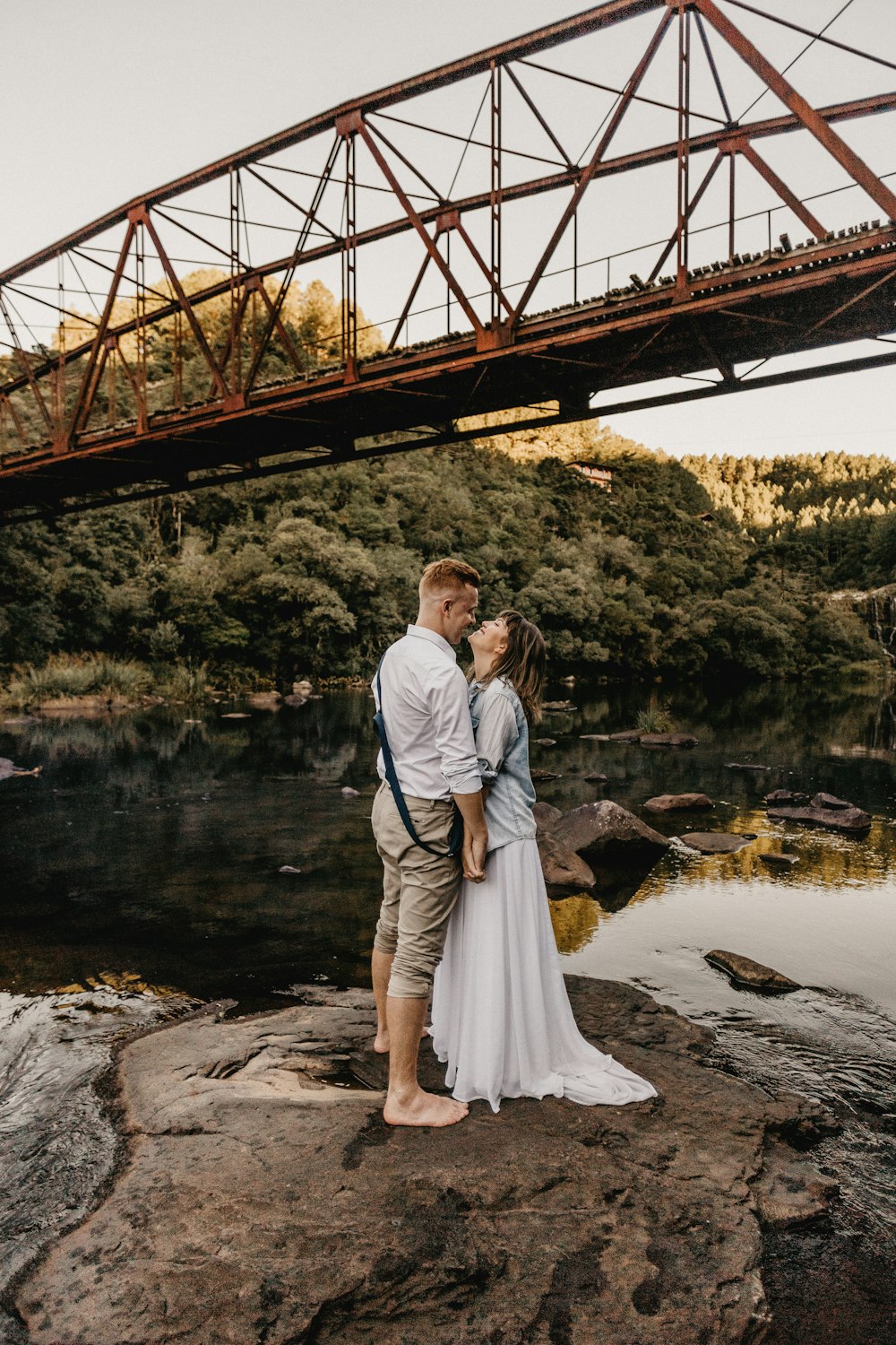 man and woman kissing under the bridge