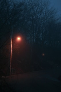 A haunting image of a deserted street at night with a single glowing streetlamp