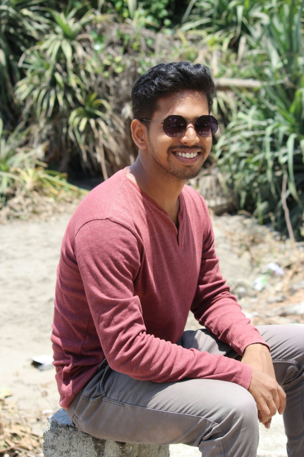 shallow focus photo of man in maroon long-sleeved shirt wearing black sunglasses