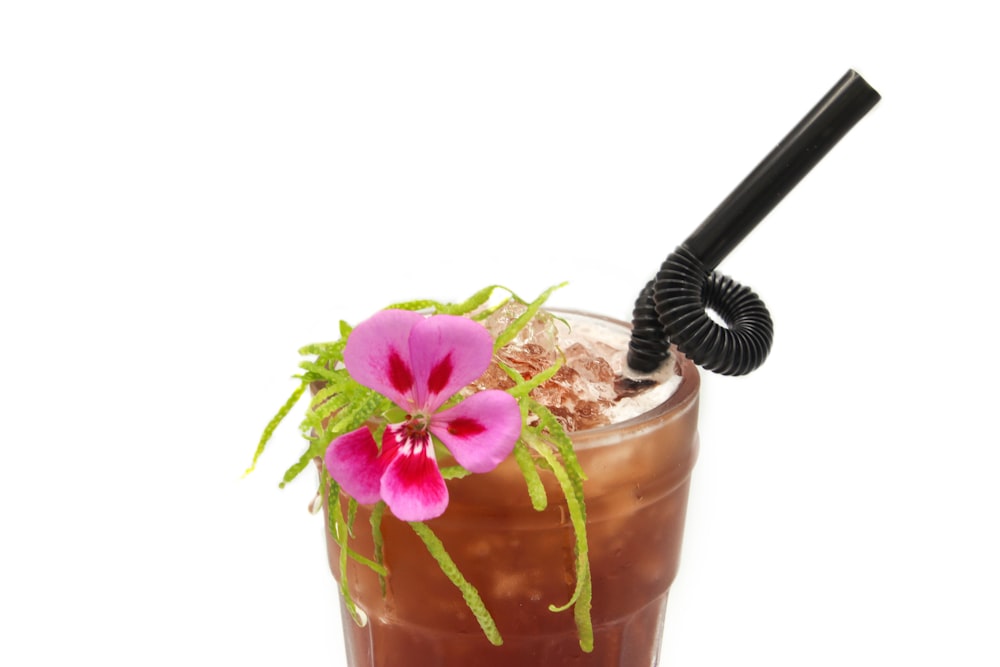 purple flower on top of glass with black plastic straw