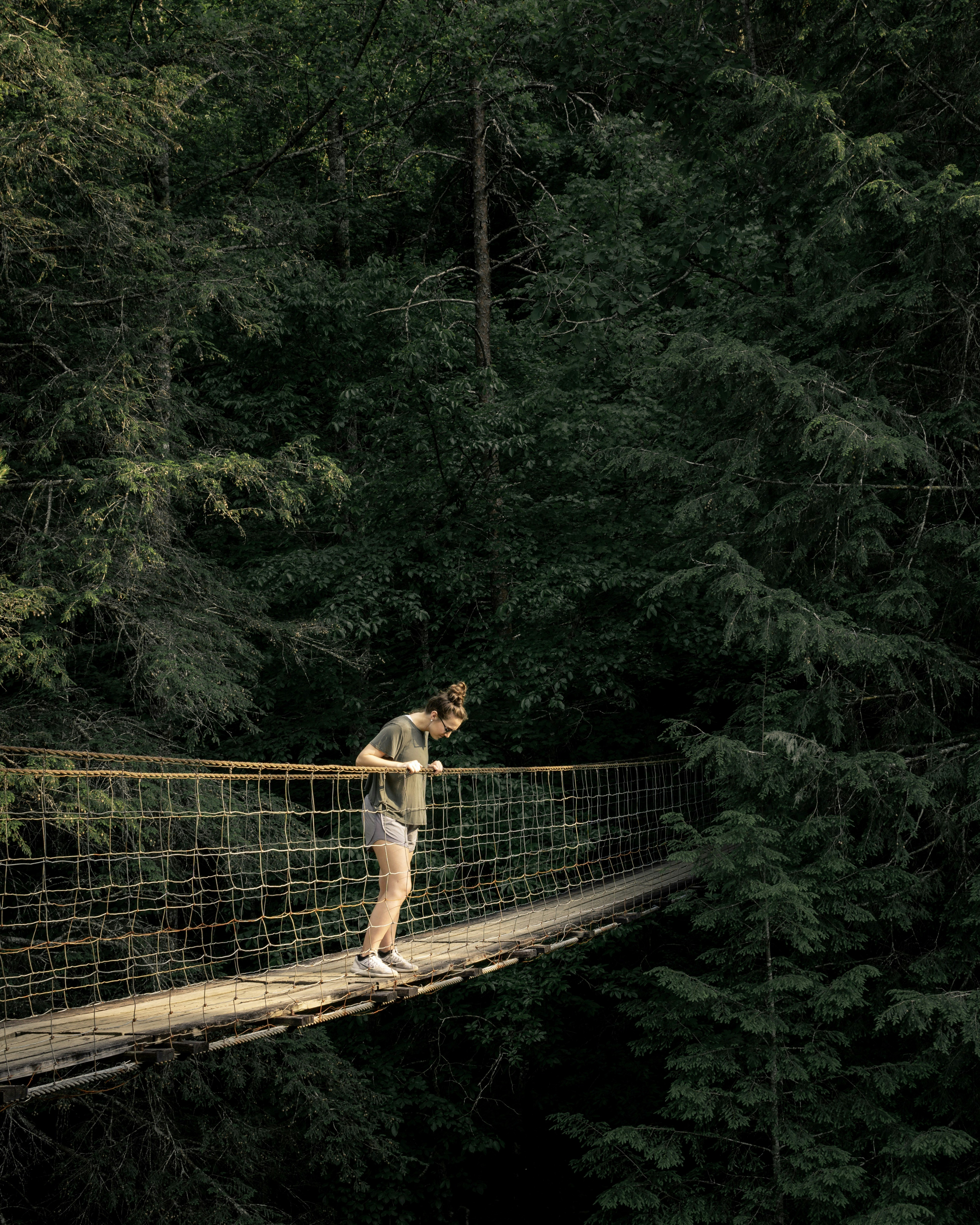 woman viewing downward on hanging bridge