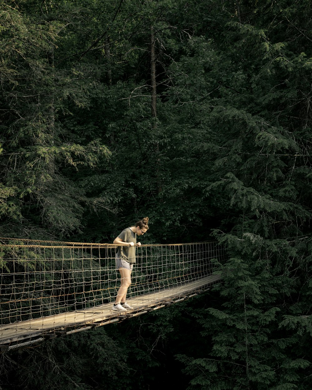 woman viewing downward on hanging bridge