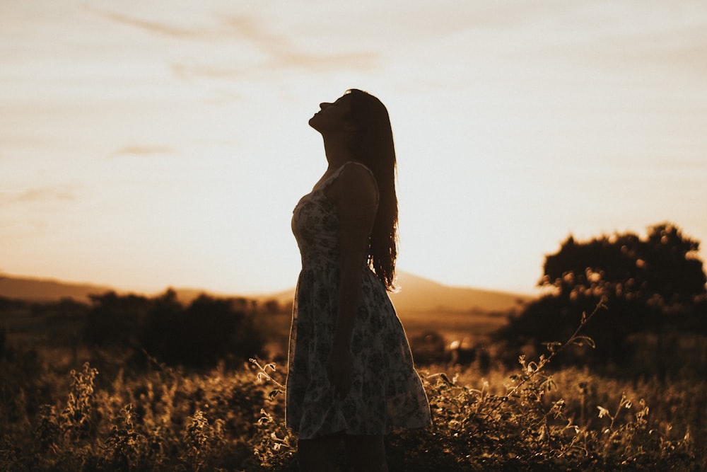 woman wearing floral dress standing on brown grassland with a sense of belonging