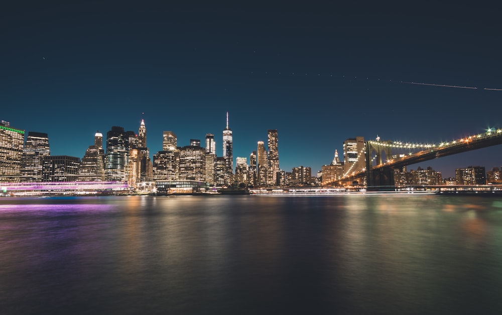 turned on lights of buildings and bridge at night