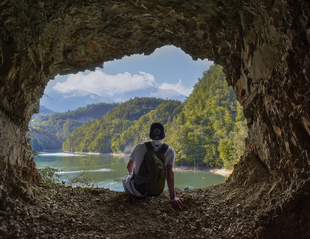man sitting on cave facing sea