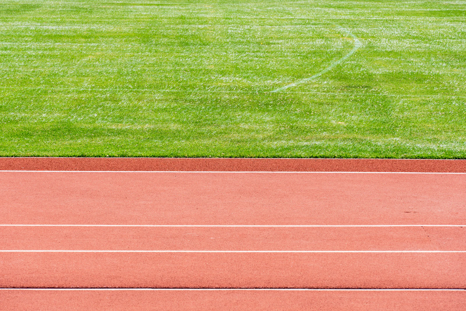 An empty running track beside a green sports field