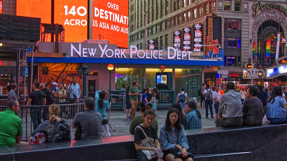 people sitting and others are walking near New York Police Department buildings