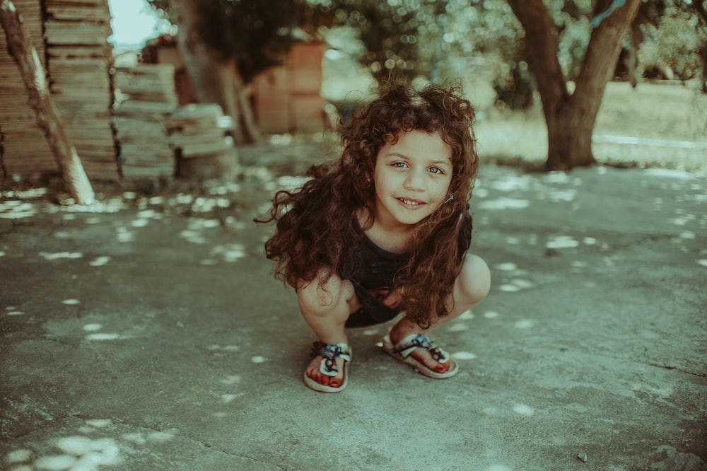 girl squatting near tree during daytime