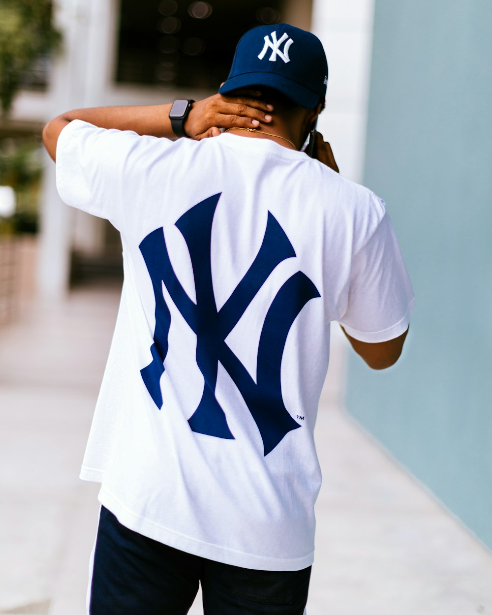 Man wearing white and blue New York Yankees t-shirt walking while