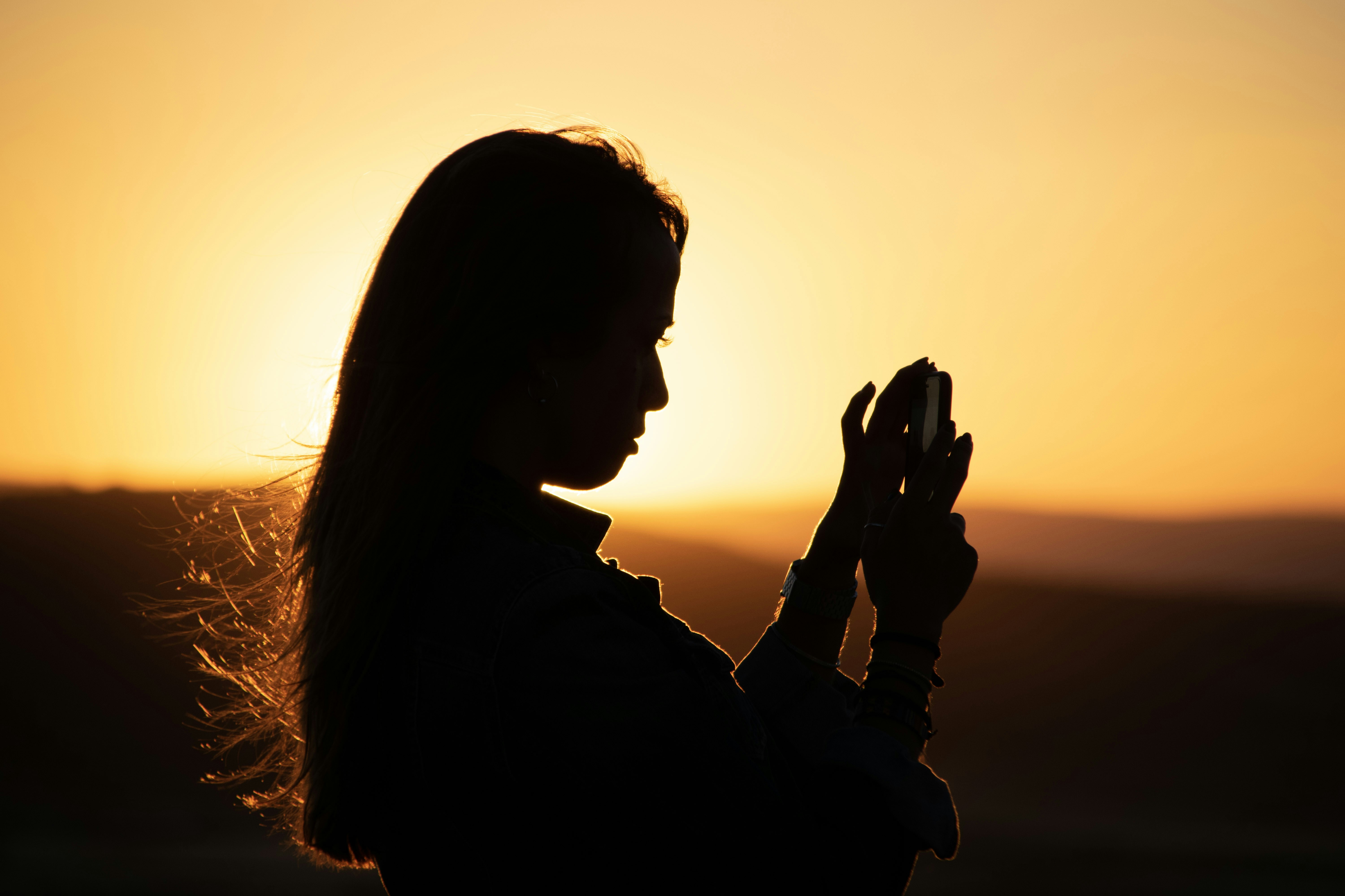 A girl takes a picture on her phone during a sunset music festival in Don Quixote's Windmills.