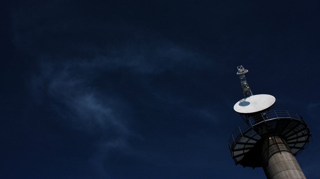 white and black satellite dish under dark-blue skies