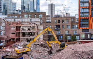 yellow backhoe on ground near buildings