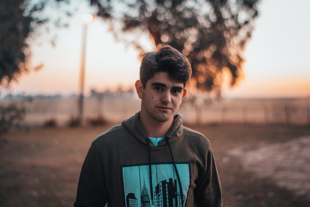 man wearing gray and green pullover hoodie standing on ground
