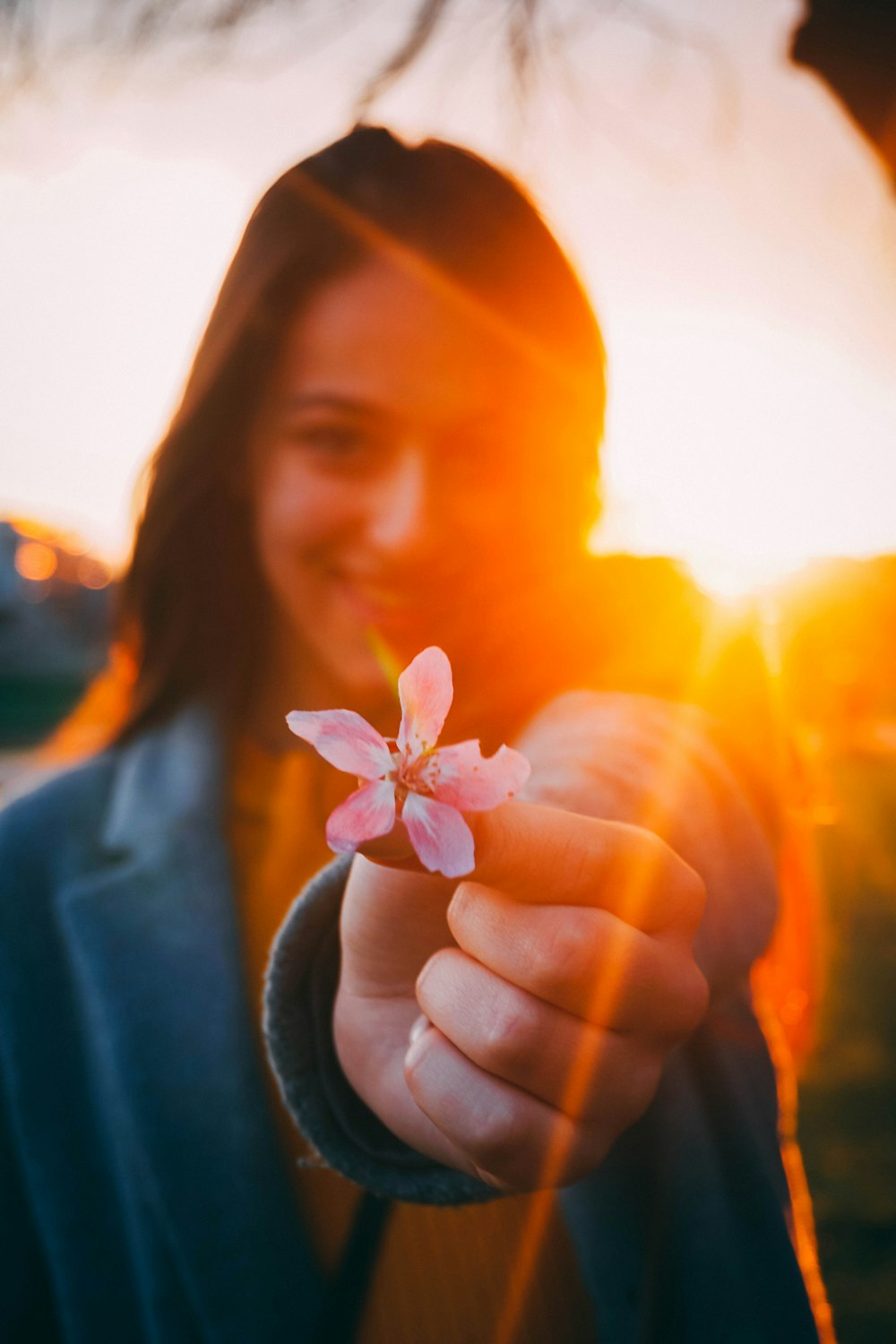 woman holding a pink flower at sunset