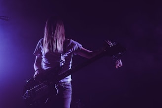 woman in white shirt playing electric guitar
