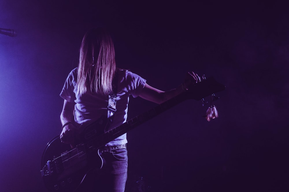 femme en chemise blanche jouant de la guitare électrique