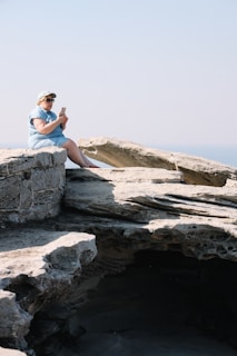 A hiker using a smartphone connected via Star Wifi CA satellite service on a rocky outcrop with forested valleys below.