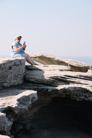 A hiker using a smartphone connected via Star Wifi CA satellite service on a rocky outcrop with forested valleys below.