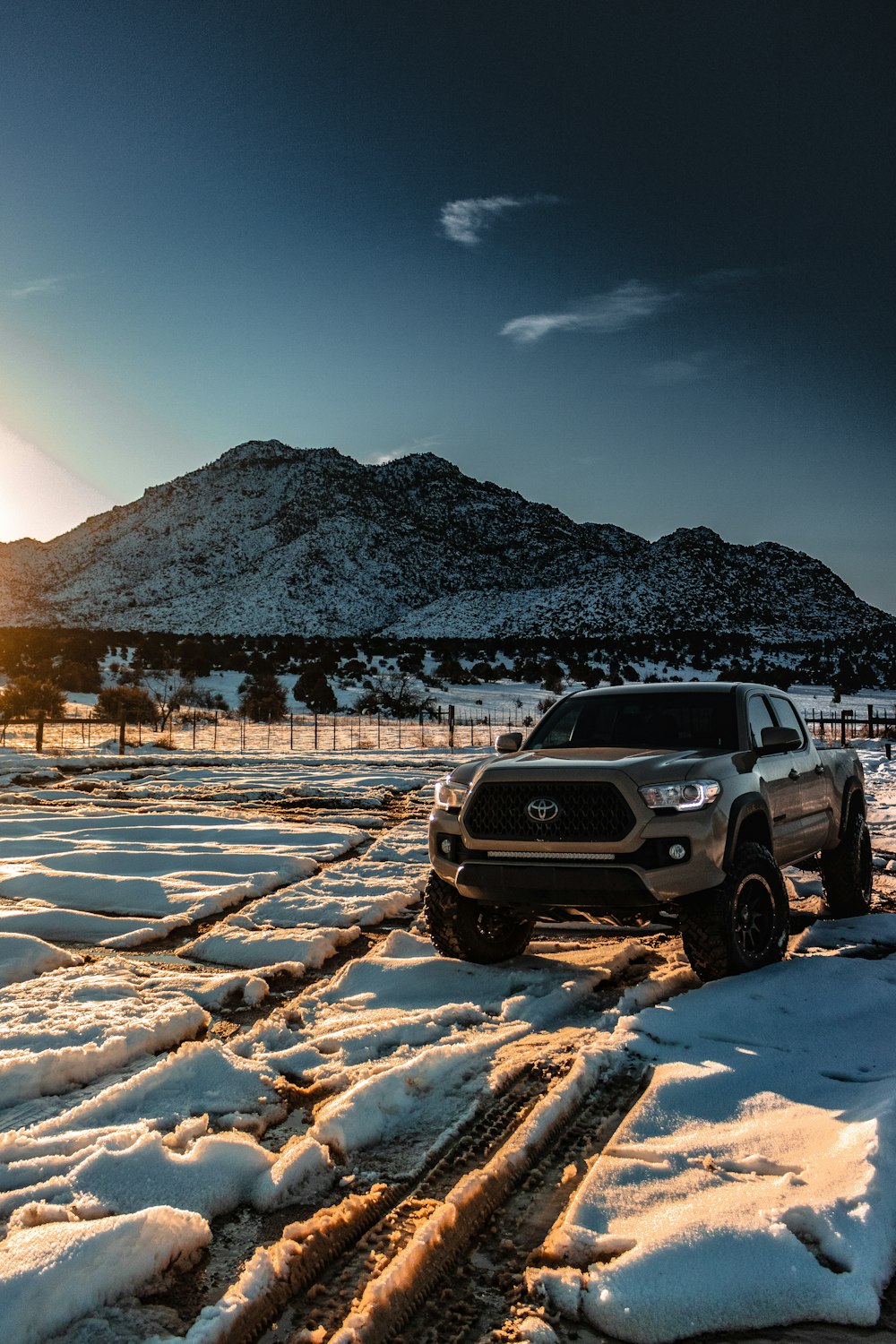 grey Toyota crew cab pickup truck on snow capped field during daytime