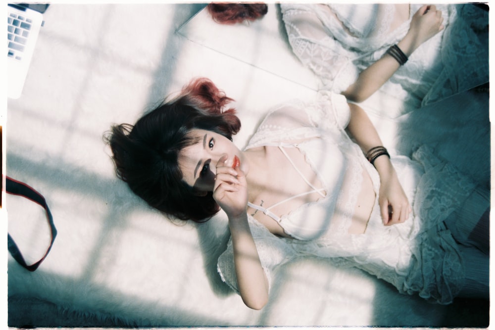 woman wearing white bralette lying on white fur area rug