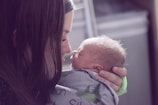 A close-up of a mother gently cradling her newborn.