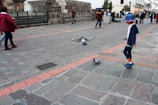 A playful scene of children wearing Instinct Paris accessories, like hats and scarves, on a city street.