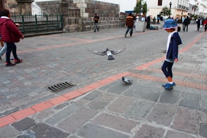 A playful scene of children wearing Instinct Paris accessories, like hats and scarves, on a city street.