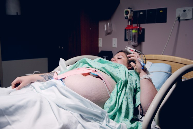 A clinician reviewing monitoring equipment readouts beside a hospital bed