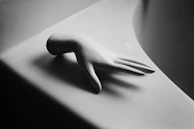 Minimalist composition featuring a hand with elegant cream-colored nails resting on a black velvet surface.