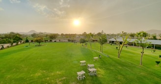 The elegant clubhouse with a sprawling lawn and outdoor seating under warm sunset light.