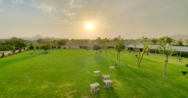 The elegant clubhouse with a sprawling lawn and outdoor seating under warm sunset light.