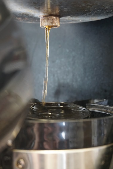 Close-up of a sleek beverage filling machine in action, with stainless steel parts and clear liquid flowing into bottles.