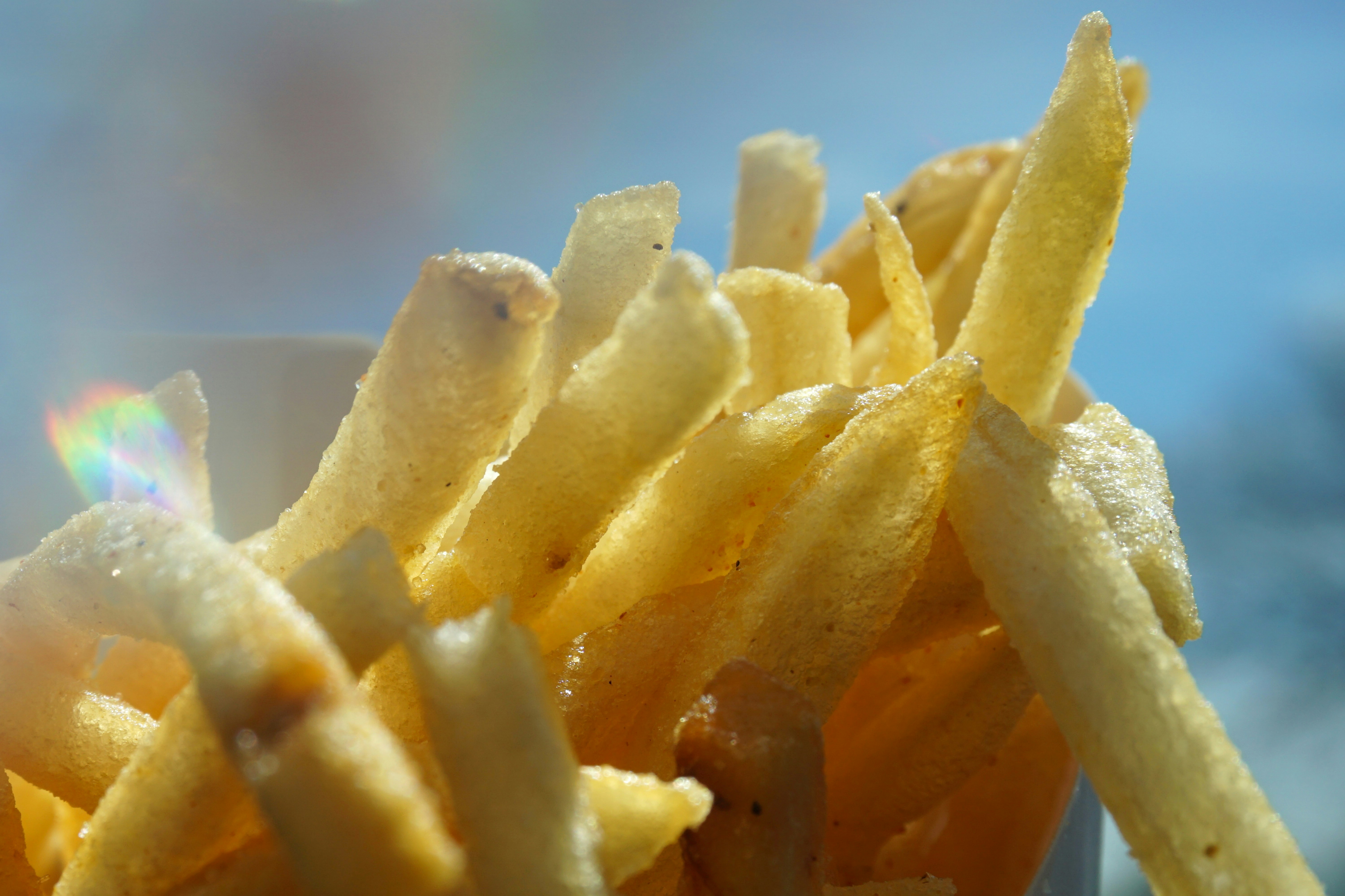 Golden french fries on bright white surface, clean food photography lighting