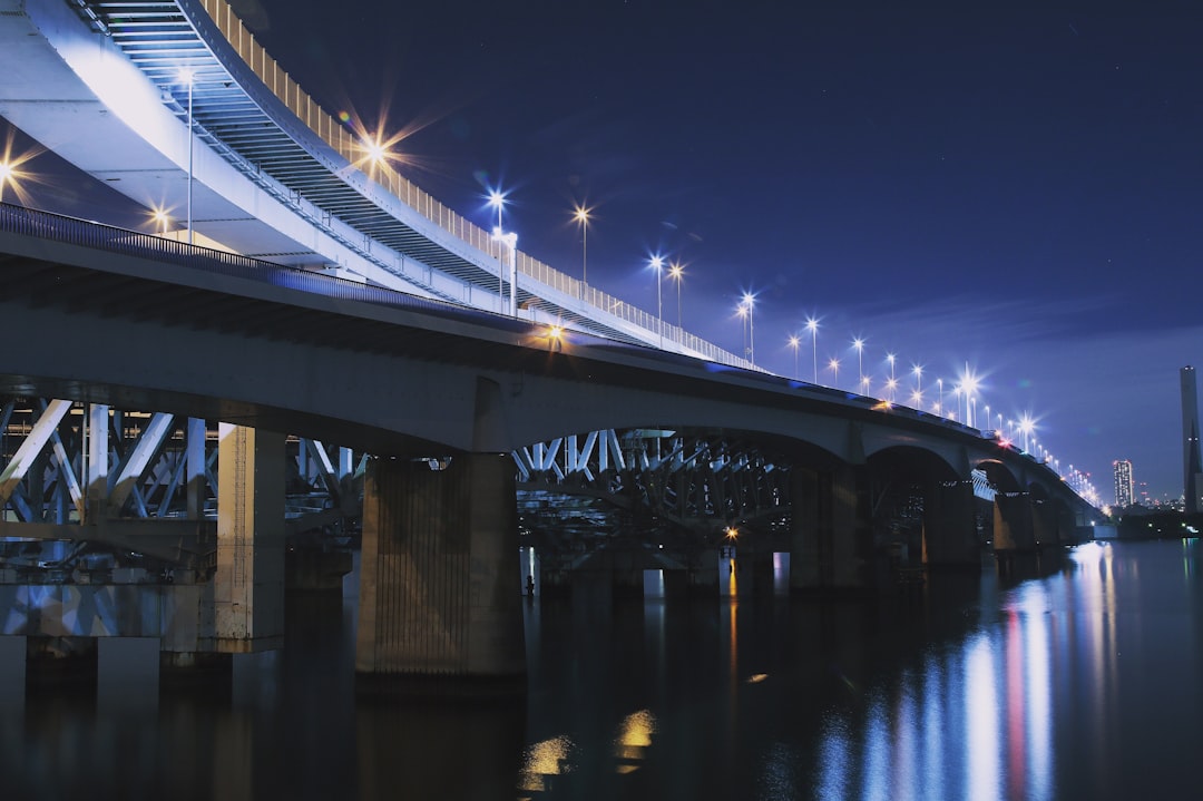lighted bridge above calm body of water at night