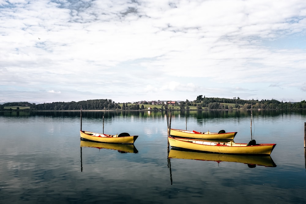 three yellow boats at middle of lake