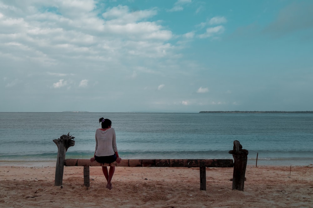 woman sitting on bench facing sea
