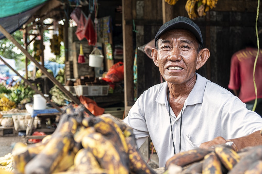 hombre sentado y sonriendo mientras vende plátanos