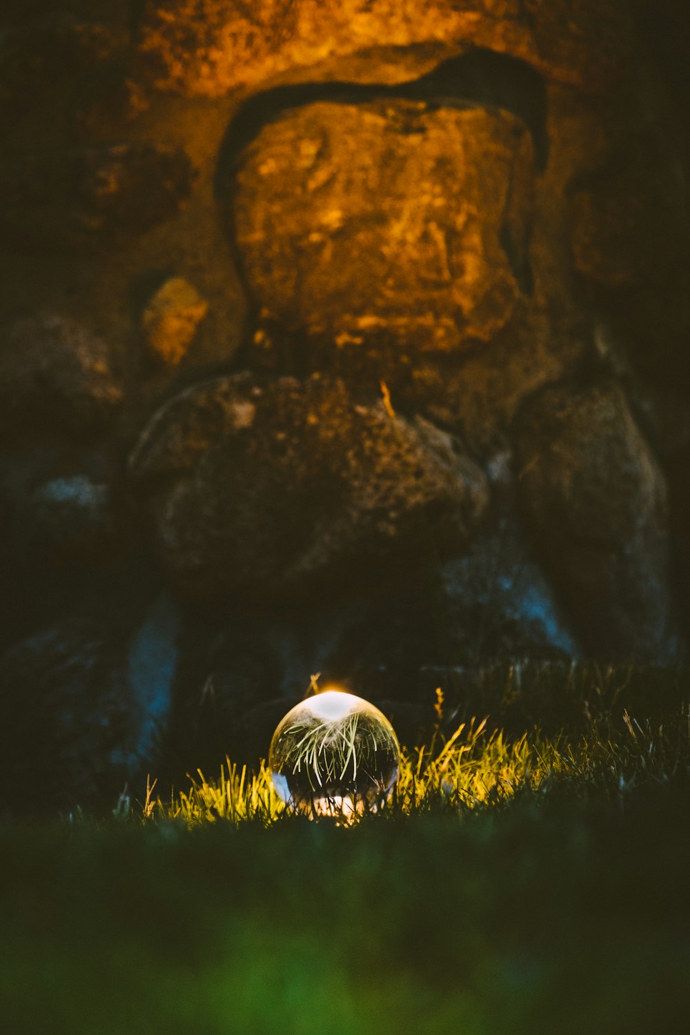 a glass ball sitting on top of a lush green field