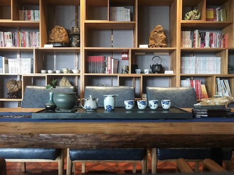 a wooden table topped with cups and vases