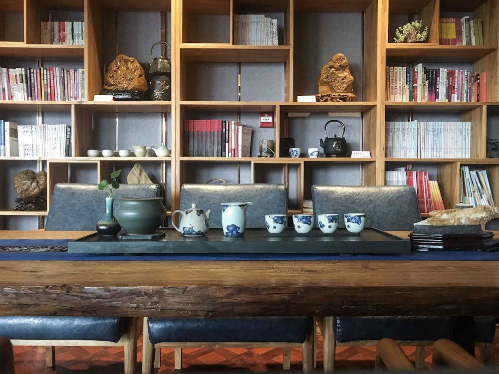 a wooden table topped with cups and vases