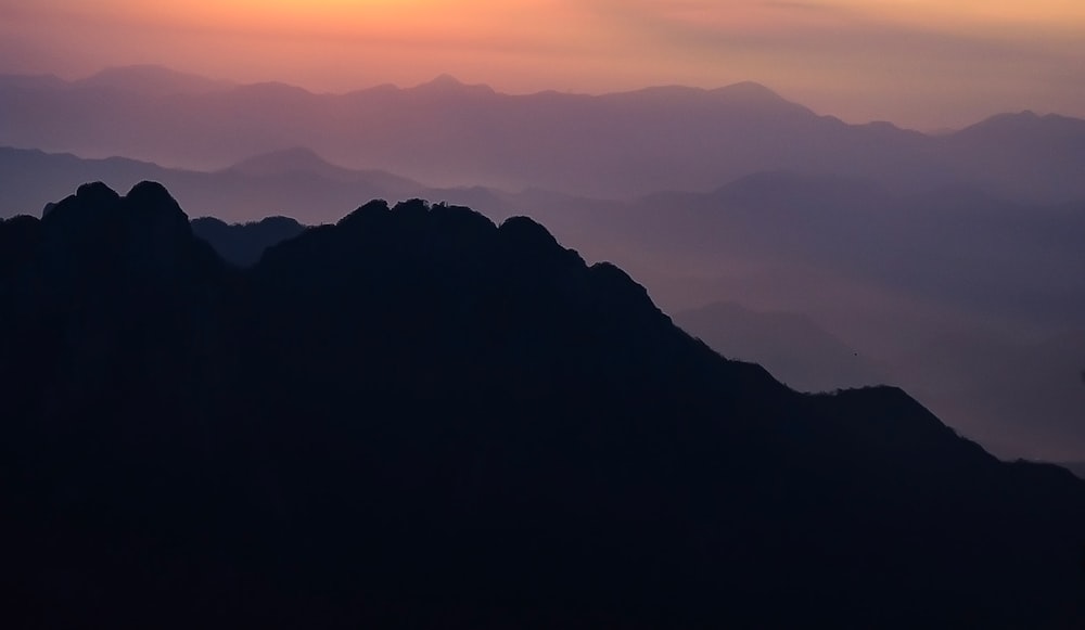 the sun is setting over a mountain range