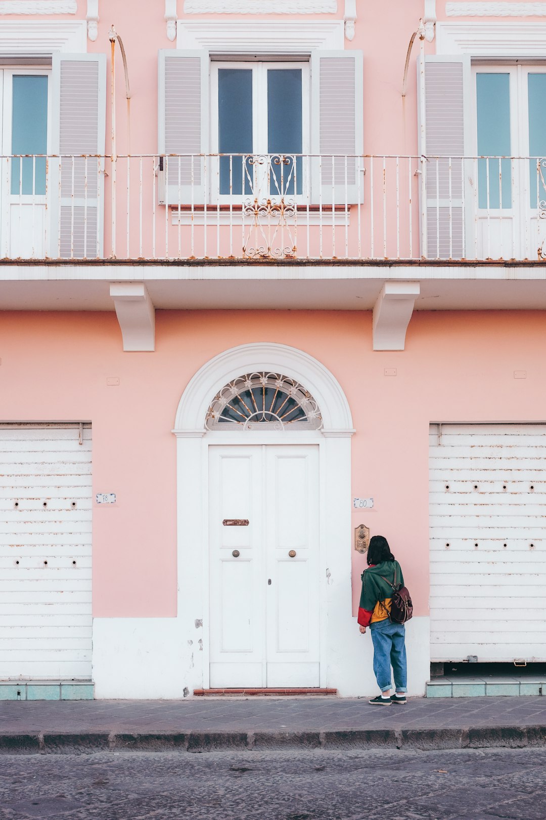 person standing in front of pink and white painted building