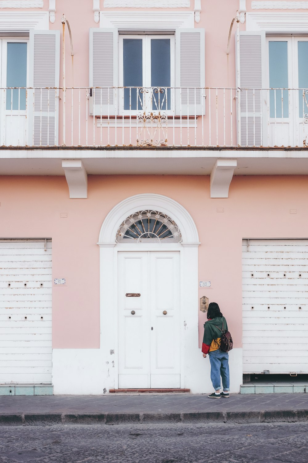 pessoa em pé na frente do edifício pintado de rosa e branco