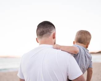 man carrying baby near the ocean