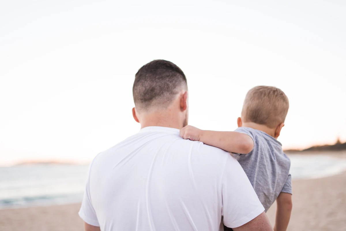 A parent gently bonding with their child near the water, representing warmth and family support