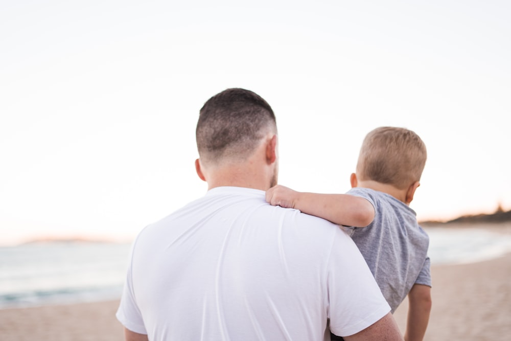 man carrying baby near the ocean