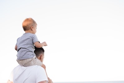 man in white shirt carrying boy parents google meet background