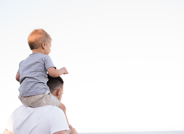 man in white shirt carrying boy