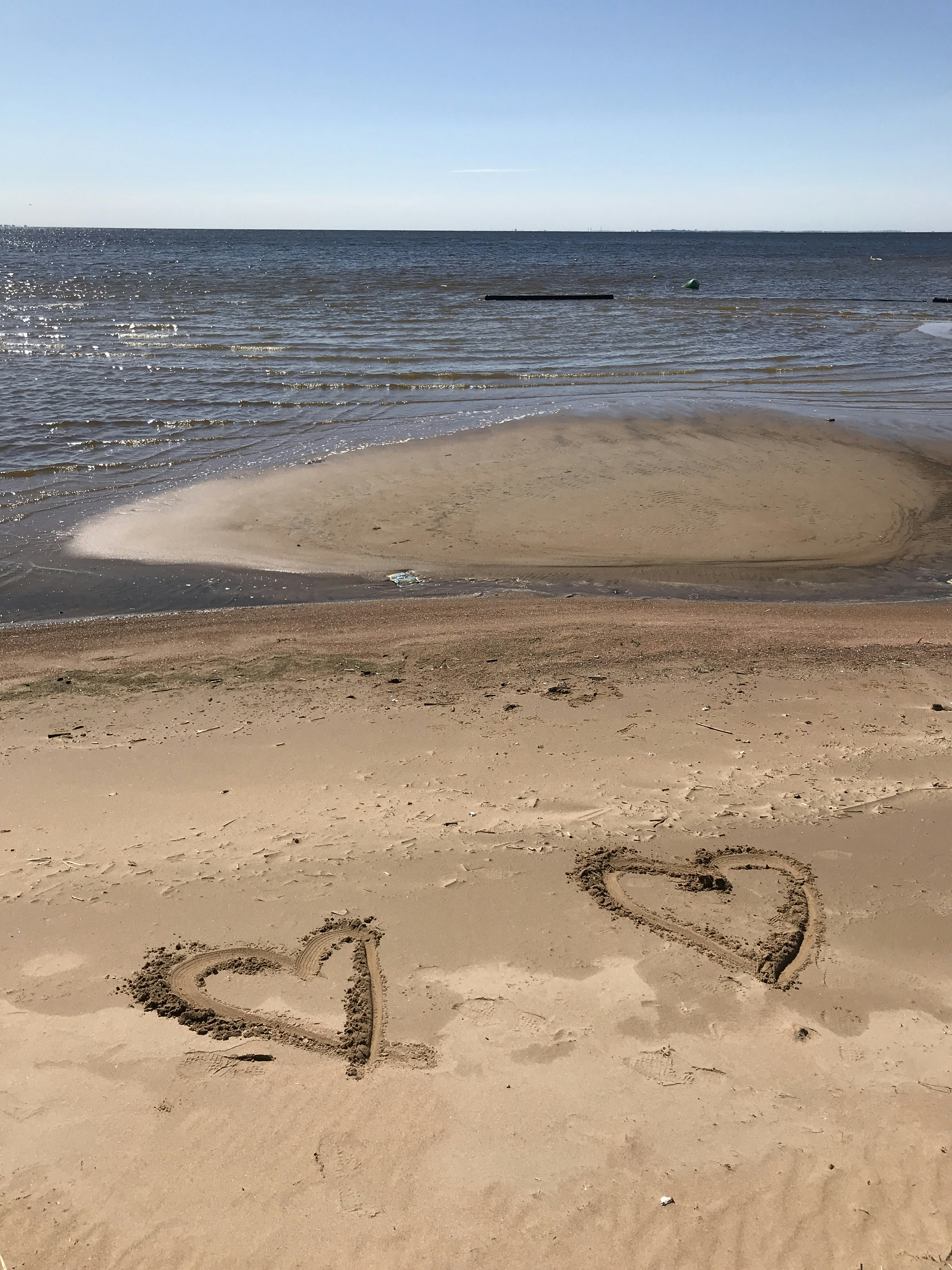 two hearts drawn in brown beach sand