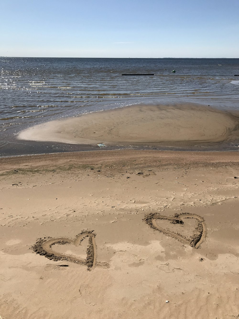 two hearts drawn in brown beach sand